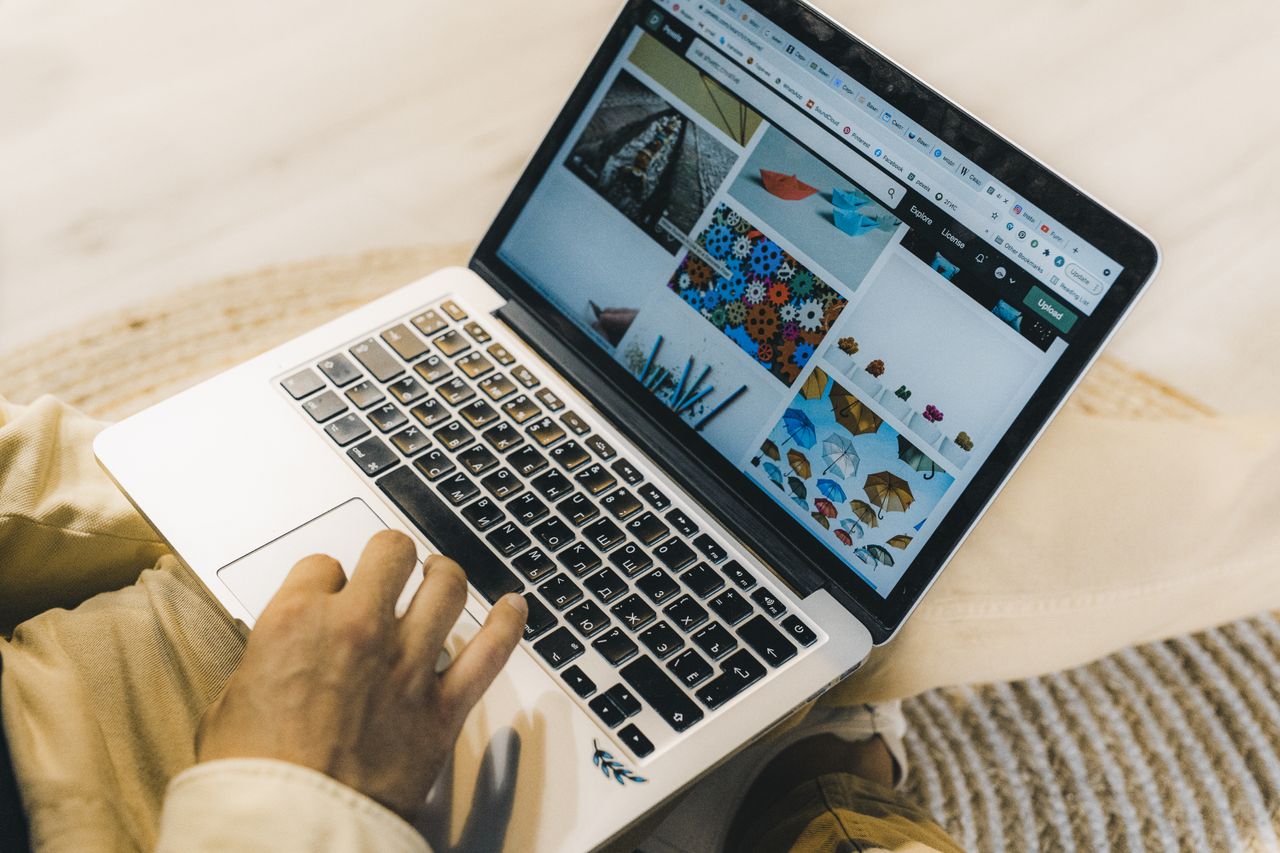 Une personne qui utilise un ordinateur portable pour parcourir des sites de photos de stock. Travail en freelance dans un cadre chaleureux.